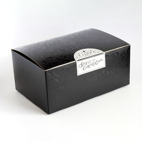 Curio Spice Co. gift wrap box, matte black with glossy details and sealed with a sticker that reads "Spices for the Curious Cook".