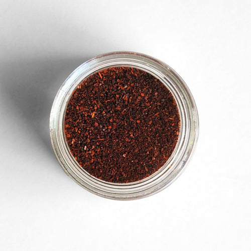 Curio Spice Co. fair-trade single origin sustainable California ground ancho chilies in a glass jar from above.