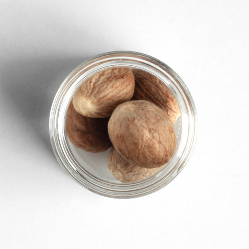 Curio Spice Co. fair-trade single origin sustainable Sri Lankan whole nutmeg in a glass jar from above.