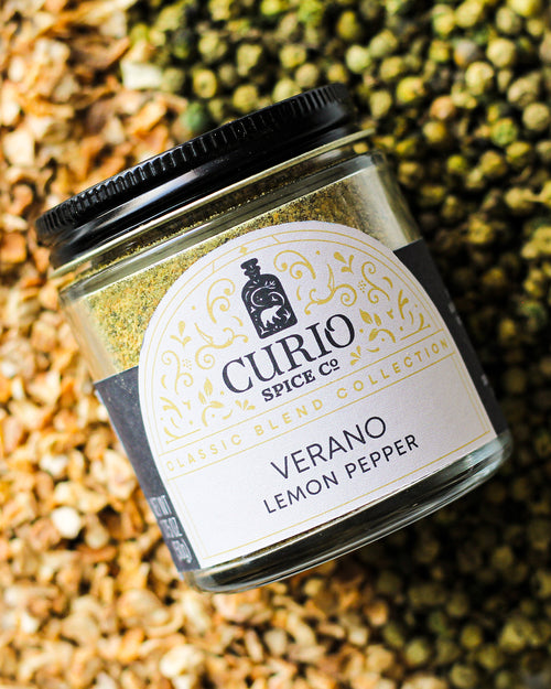 Curio Spice Co. Classic Blend Verano Lemon Pepper on a bed of green peppercorn and lemon peel.